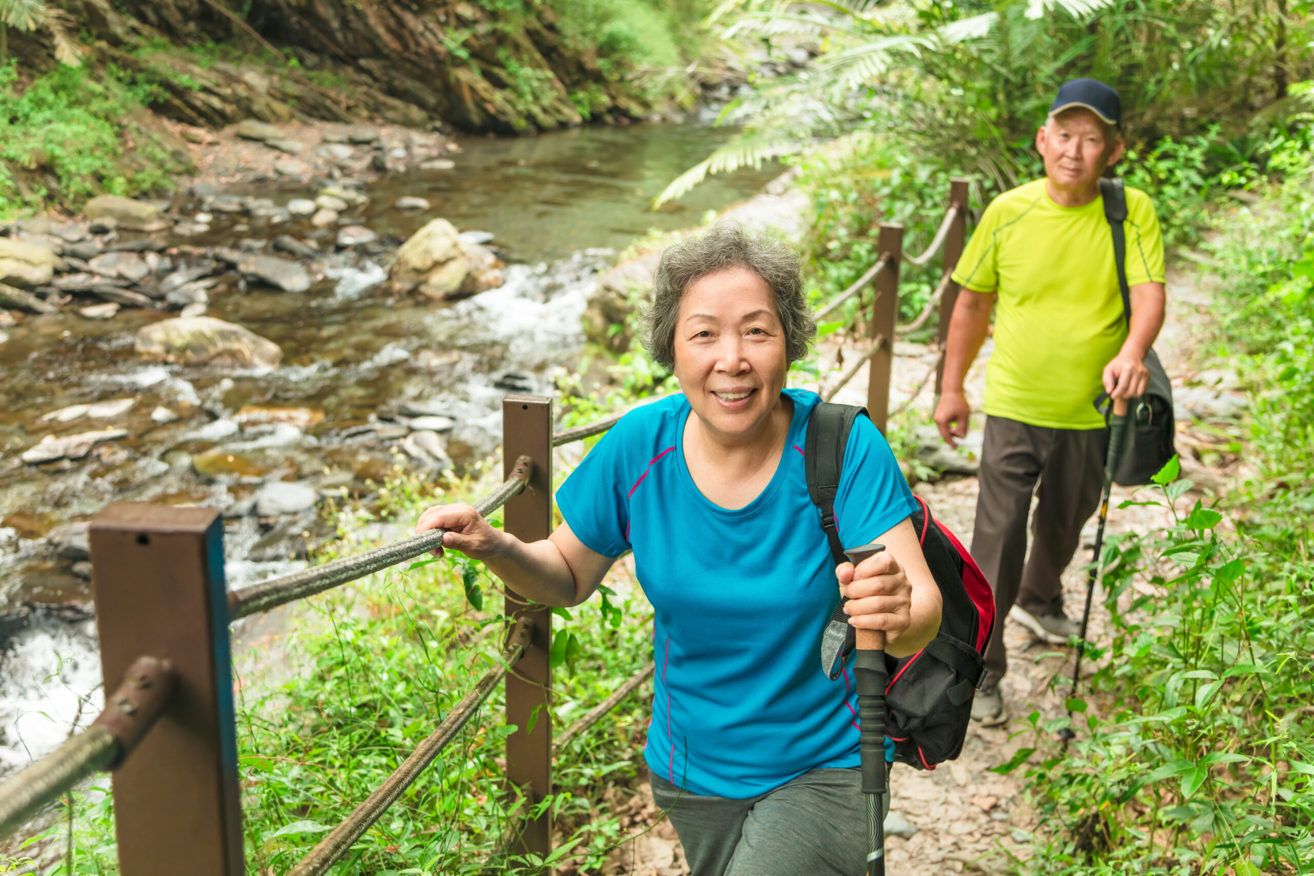 Happy Asian senior couple hiking in nature park
